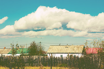 a country landscape with houses and clouds above. toned.