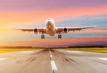 Passenger airplane landing at sunset on a runway.