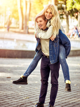 Adventure trips for couples. Spring people walking park and kissing. Summer friends walk outdoor. Weekends first date of two young person. He carries girl on his back. Toning of spring photo.