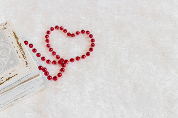 Heart shape made from red necklace on white background