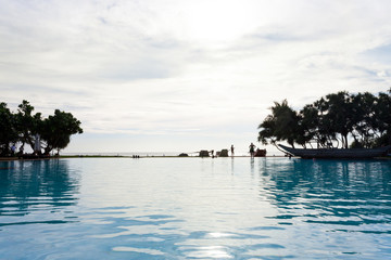 Ahungalla, Sri Lanka - DECEMBER 2015 - A view across a hotel pool during sundown while people are talking at the beach