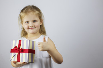 Happy girl holding gift box and showing thumbs up