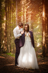 Just married loving couple in wedding dress and suit in a forest.