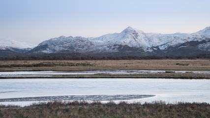 Beautiful Winter sunrise landscape image of Mount Snowdon and other peaks in Snowdonia National Park