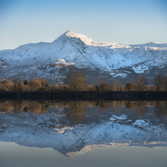 Beautiful Winter sunrise landscape image of Mount Snowdon and other peaks in Snowdonia National Park