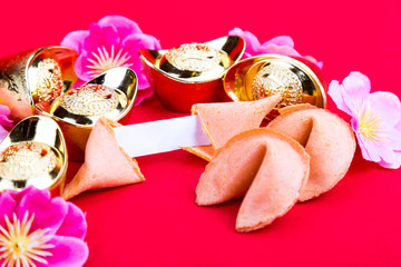 Fortune cookies, decorative gold nuggets, plum blossom flowers red background