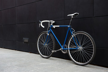 Fototapeta na wymiar Vintage blue city bicycle against a black wall