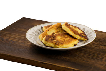 Syrniki on a white plate on a wooden board. Cheese pancakes. Breakfast.