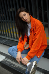 Young fashionable teenager girl walks around the city in the summer in a fashionable jacket and jeans