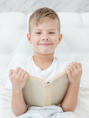 Happy boy with book on the  bed