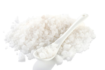a pile of sea salt with a ceramic spoon on a white background. isolate.