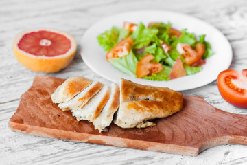 cooking a healthy fresh salad with chicken, grapefruit, cheese and tomatoes