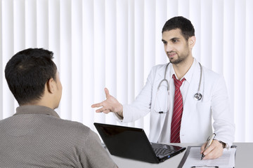 Obraz premium Young doctor talking with his patient in hospital