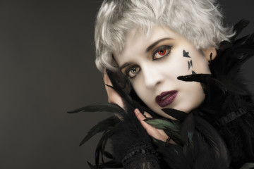 Androgynous witch girl, with red-green eyes and black feathers, crying black stars