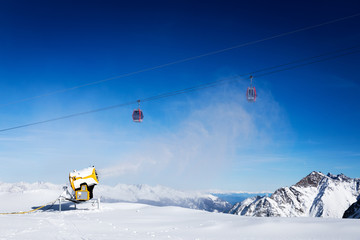 Fototapeta na wymiar snow gun working against blue sunny sky at ski resort