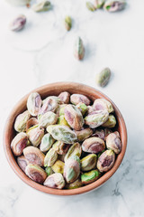 Roasted and salted pistachios nuts on marble background