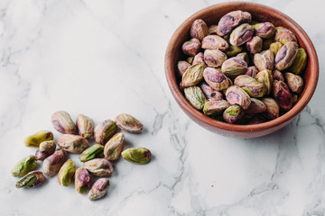 Pistachios in wooden bowl on marble background with copy space 