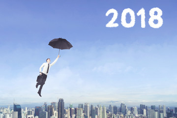 Male entrepreneur with umbrella and number 2018