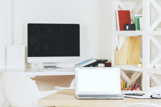 Designer workspace with blank white laptop