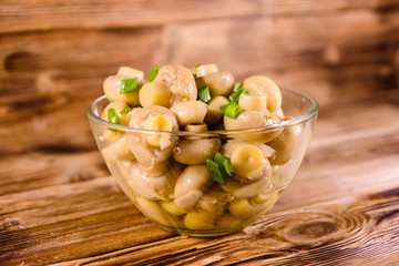 Canned mushrooms in a glass bowl on wooden table