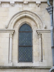 Fototapeta na wymiar Visages sculptés de part et d'autre d'un vitrail d'une église