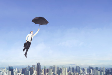 Caucasian businessman flying with an umbrella