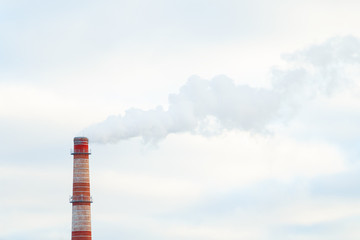 Industrial smoke from the red chimney on background of blue sky. Environmental pollution