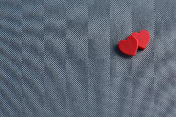 Fototapeta premium Two Red hearts on grey fabric texture background.