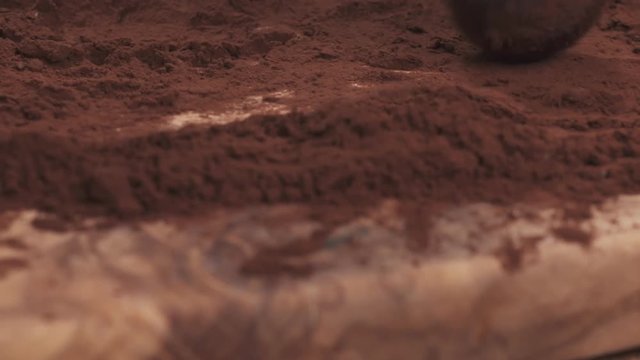 Slow motion handheld shot put truffles in cocoa powder on board