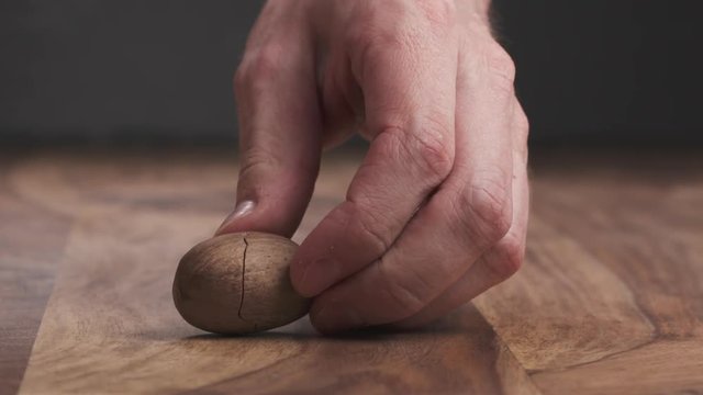 Slow motion man hand break pecan nut on table