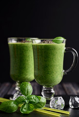 Blended green smoothie with ingredients on wooden table