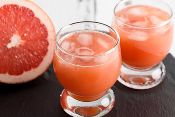 Grapefruit juice and ripe grapefruits on a wooden background