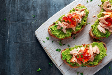 Homemade Toast sandwich with Salmon, Avocado and chilli jam on wihte wooden board. healthy food