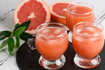 Grapefruit juice and ripe grapefruits on a wooden background