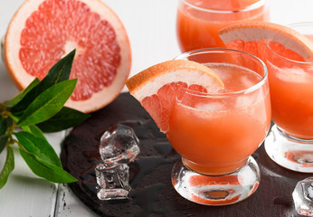 Grapefruit juice and ripe grapefruits on a wooden background