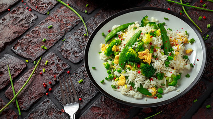 Fried rice with vegetables, broccoli, peas and eggs in a plate. soy sauce. healthy food