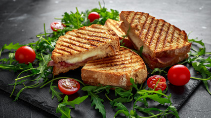 Grilled Bacon, cheese sandwich and served on stone platter with arugula and tomatoes