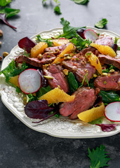 Duck breast fillets steak salad with orange halves, radishes and crushed pistachios