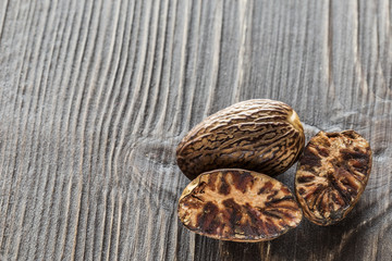 Nutmegs, whole and half-wool, on a wooden background, macro, dark background, tree structure and internal nut structure