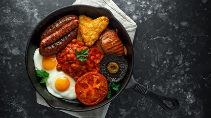 Full English breakfast with bacon, sausage, fried egg, baked beans, hash browns and mushrooms in...
