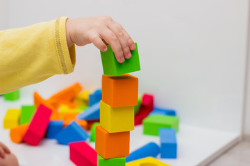 The child plays with colored cubes and puts them on each other