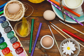 Easter Bacground. Process of Painting Easter Egg with brushes, holidays preparations, on wooden table. Flat Lay. Top View.