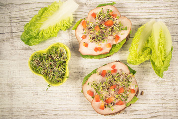 Sandwiches with lettuce, ham and broccoli sprouts.