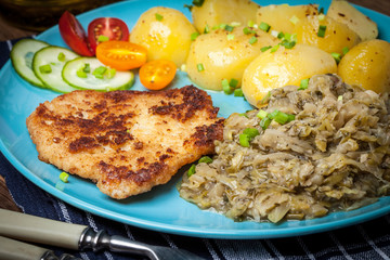 Fried pork chop, baked potatoes and fried young cabbage.