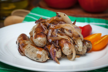 Fried Fried white sausages with onion on the plate.white sausages in a cast iron skillet.