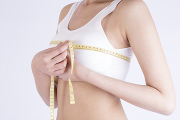 Young adult girl measuring her perfect breast - isolated on a white background