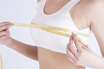 Young adult girl measuring her perfect breast - isolated on a white background