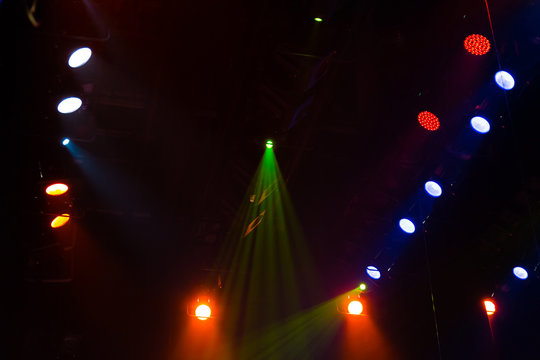 Lighting equipment on the stage of a theatre or concert hall. The rays of light from spotlights. Halogen and led light bulbs. Lens lighting.