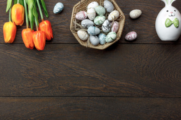Top view shot of arrangement decoration Happy Easter holiday background concept.Flat lay colorful Easter egg with tulip flower and rabbit bunny on modern brown wooden at office desk.space for mock up