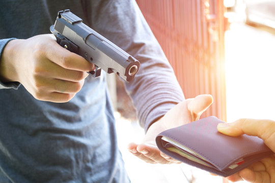 Men thieves stealing young woman bag and threatening with gun